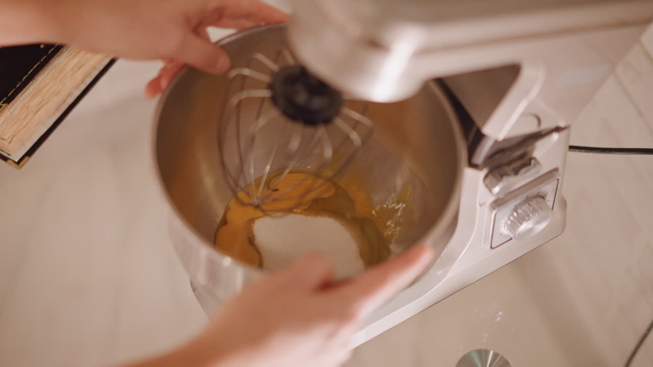 Mani caucasiche che versano le uova nella ciotola del mixer con lo zucchero, primo piano della ciotola in acciaio inossidabile e della frusta, elettrodomestico sul piano di lavoro, versamento e misurazione precisi per il ripieno della torta di zucca.