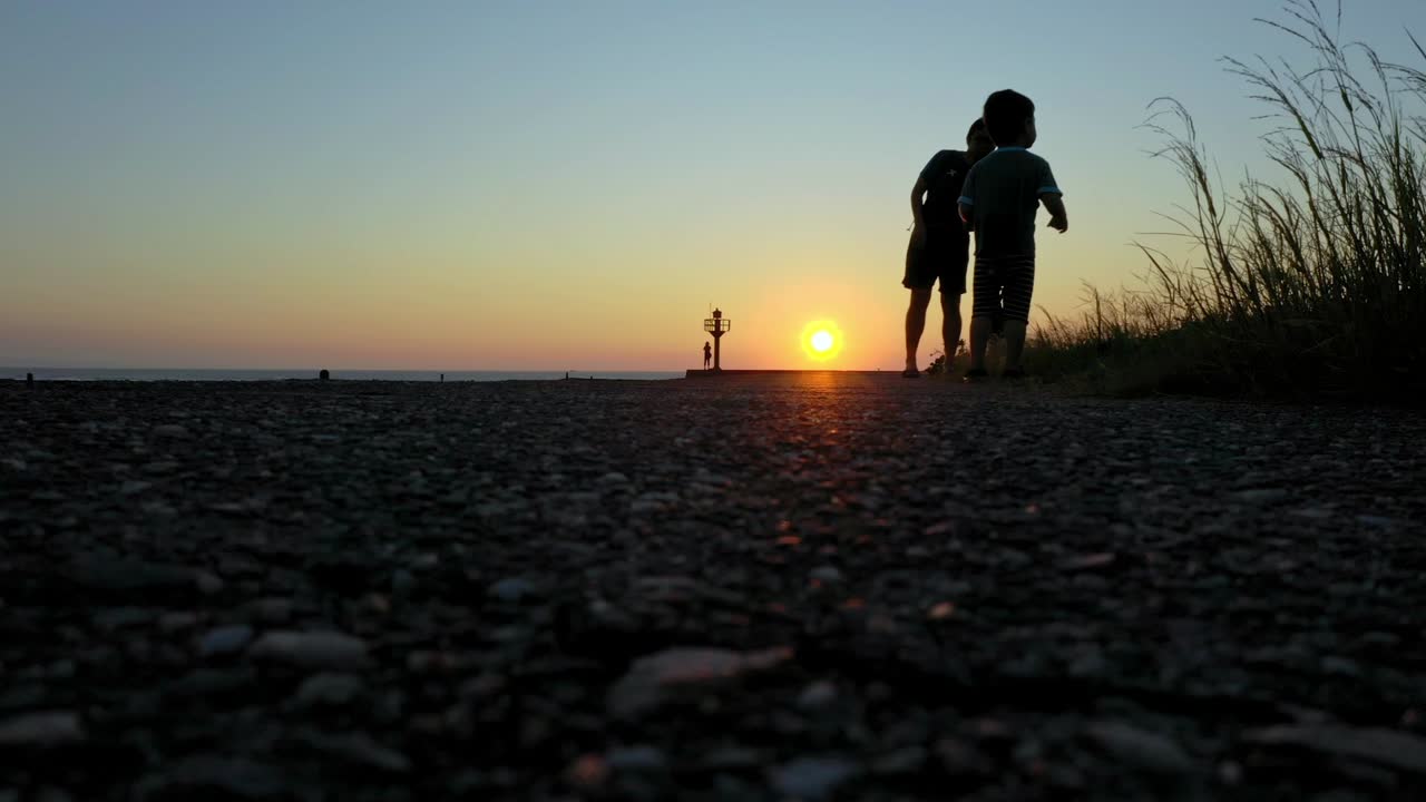 tiro de ángulo bajo que muestra la silueta de los niños jugando en la playa durante la puesta de sol en taiwán