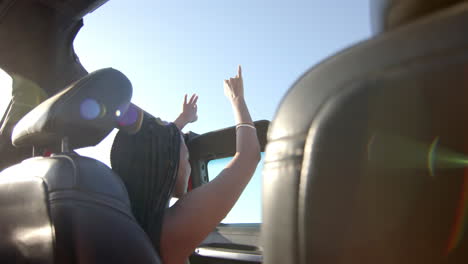 Young-African-American-woman-enjoys-a-sunny-day-in-a-convertible-car-on-a-road-trip,-with-copy-space