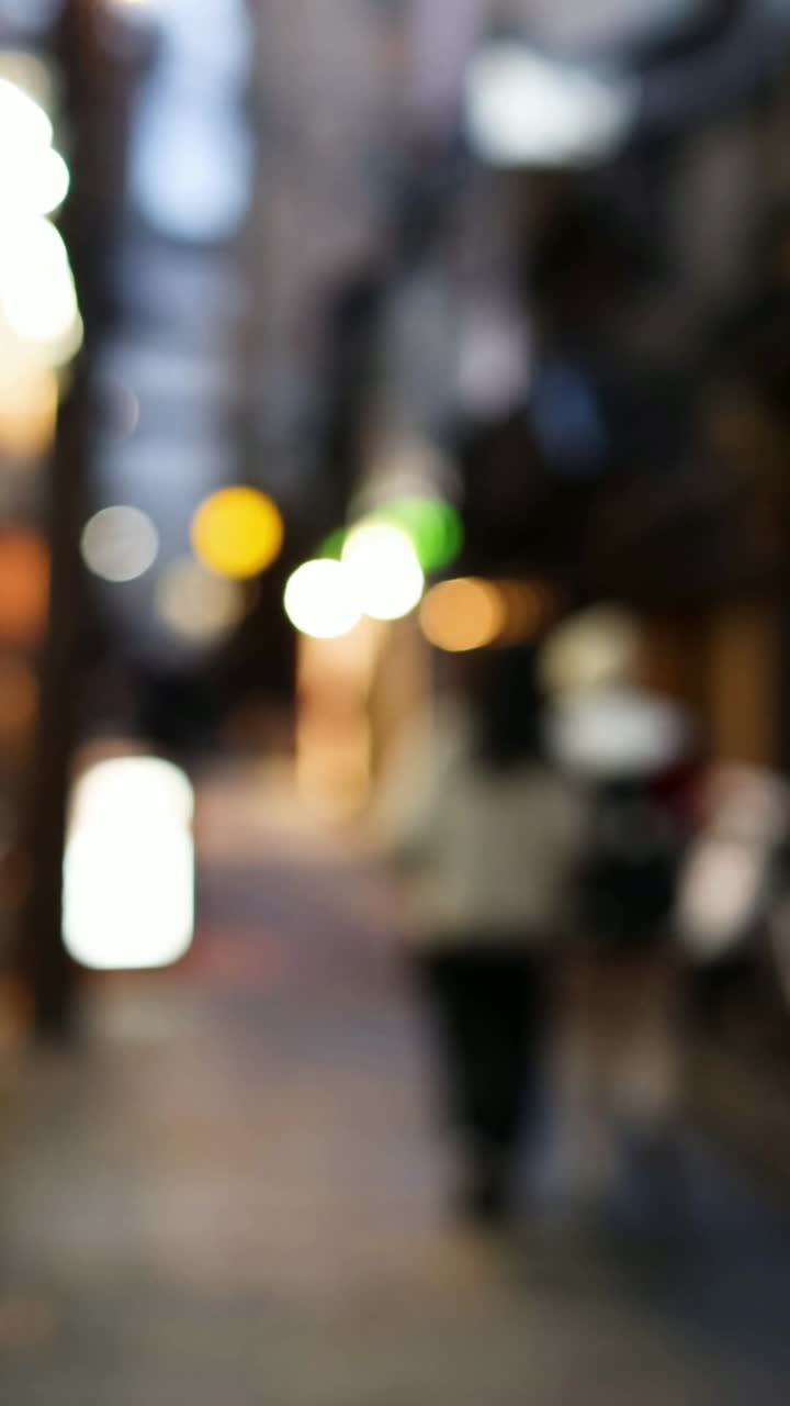 조명 된 골목길 을 고 있는 초점 이 벗어난 인물 들