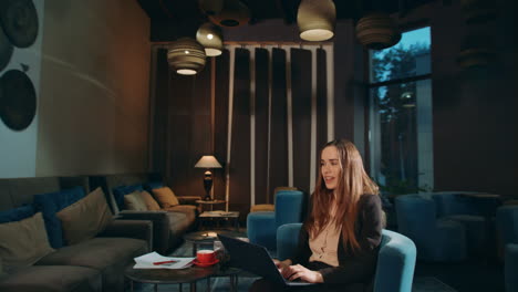 cheerful woman working laptop computer in hotel lobby. happy business woman