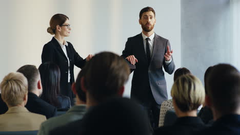 caucasian businesswoman and businessman coaching and making a speech in front of the audience at a conference