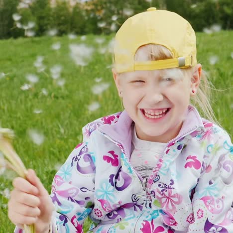 blonde girl in a yellow cap playing with dandelions