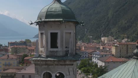 Vertigo-effect-of-a-church-in-Riva-Del-Garda-with-the-italian-alps-and-the-gardalake-in-the-background,-Drone-Shot-of-a-church-tower-in-north-Italy