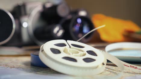 pull focus reveals vintage cine camera film reels laid on travel maps