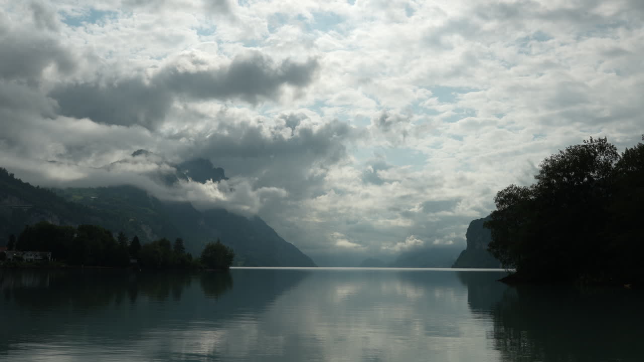 Time lapse of drifting clouds over Walensee with mountain silhouettes and lake reflections