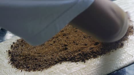 Cinnamon-and-chocolate-filling-mixture-poured-and-spread-by-hand-over-freshly-buttered-sheet-of-flat-dough-on-kitchen-table-top,-filmed-as-close-up