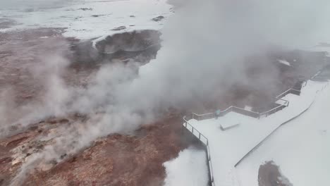 觀光客在冰島南部的雷克雅內斯半島在冬天觀看gunnuhver地熱泉上升起的蒸氣