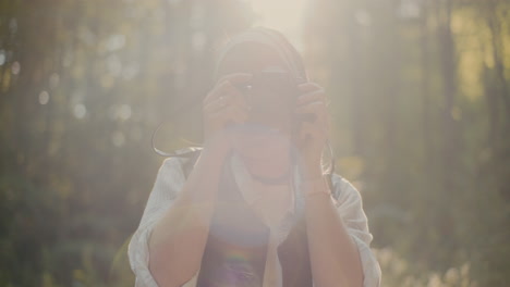 excursionista mujer fotografiando a través de una cámara en el bosque