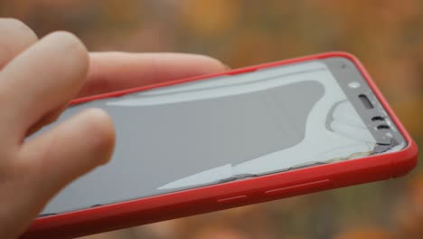 broken red phone screen. close up of woman's hand touching red mobile phone with blurred yellow green background, by sending sms messages.