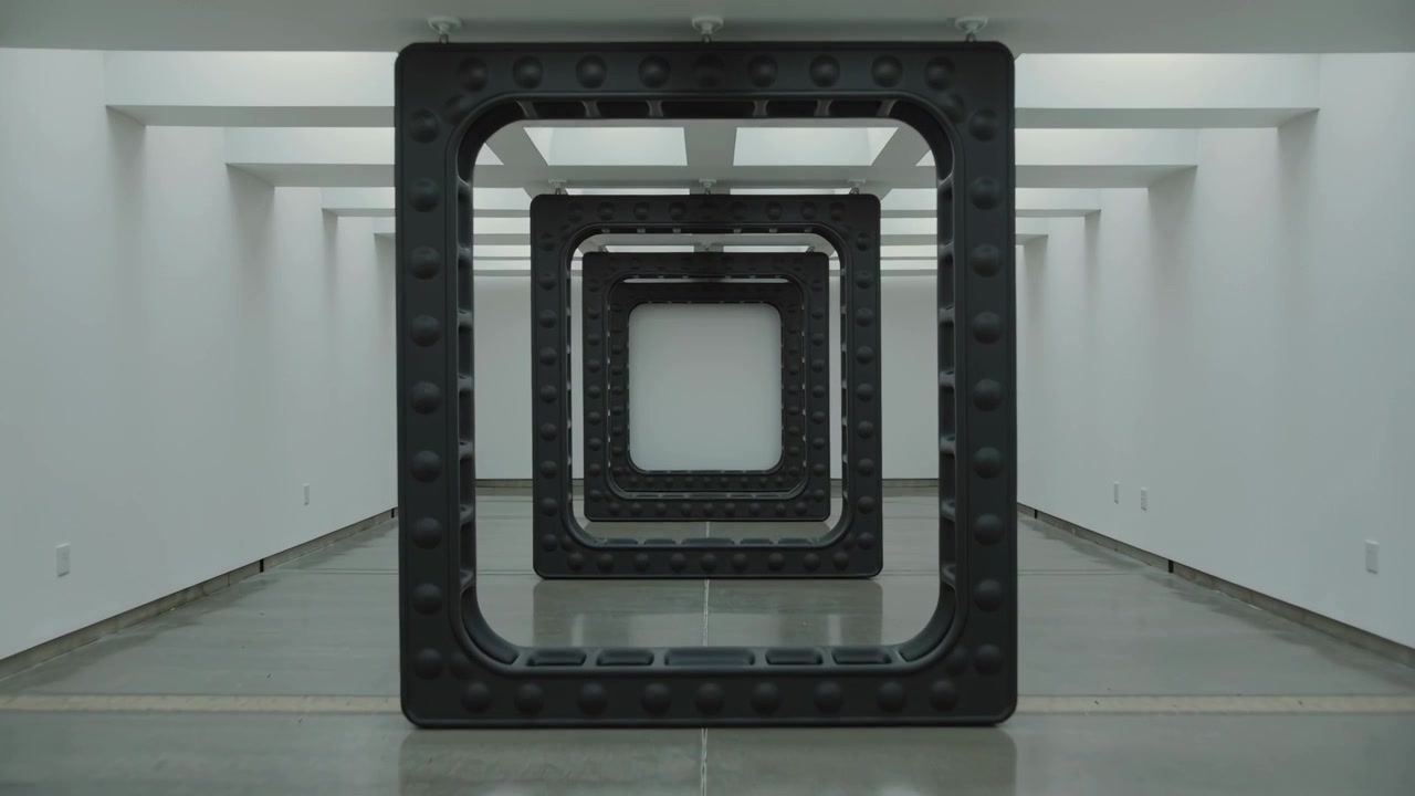 Moving camera approaching nested hollow metal frames in long white gallery hall, showing detail