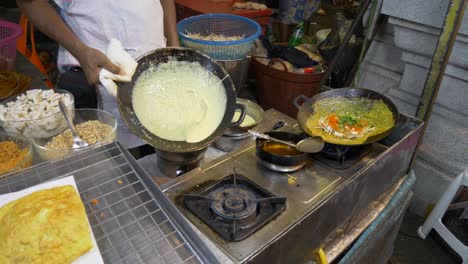 cooking omelette with vegi at asian street night market street food booth in hot summer pouring egg