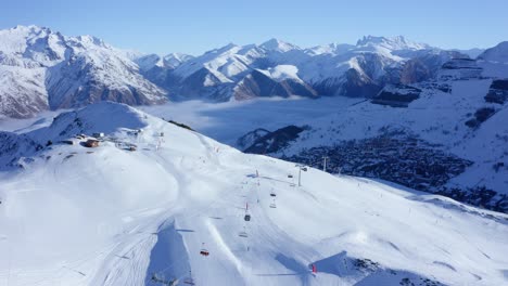 vista aérea de telesillas en movimiento y varias personas esquiando una montaña nevada en un día soleado