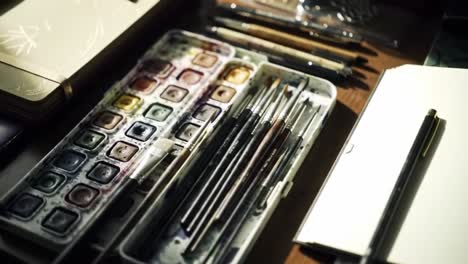 exploring the artistic workspace: a close-up view of paints, brushes, and sketchbooks capturing the creative process in vibrant natural lighting