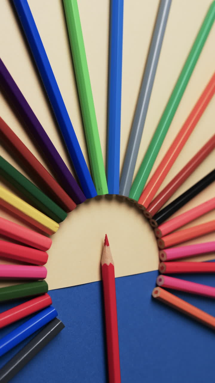 Vertical video of close up of crayons arranged on beige and blue background, in slow motion