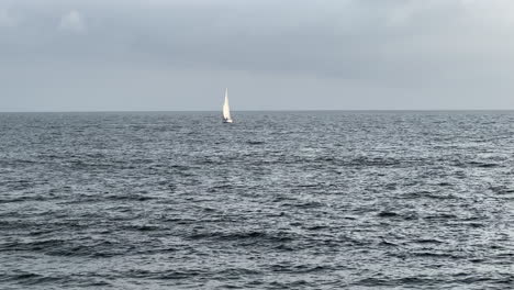 White-sailboat-navigating-the-wind-in-the-Pacific-Ocean-on-a-gloomy-California-day