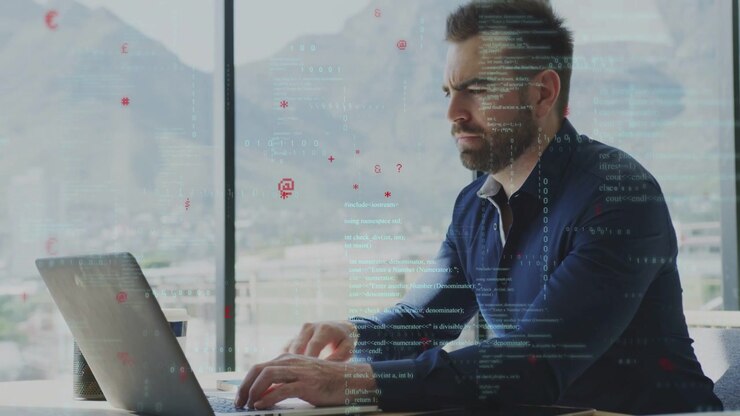 Udvikler taster på bærbar computer, der viser kode- og dataoverlejringer, analyserer software, mens han holder en pen og pauser.