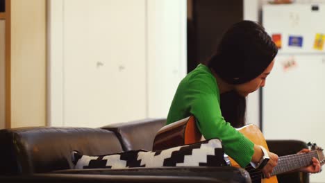 Woman-playing-guitar-in-living-room