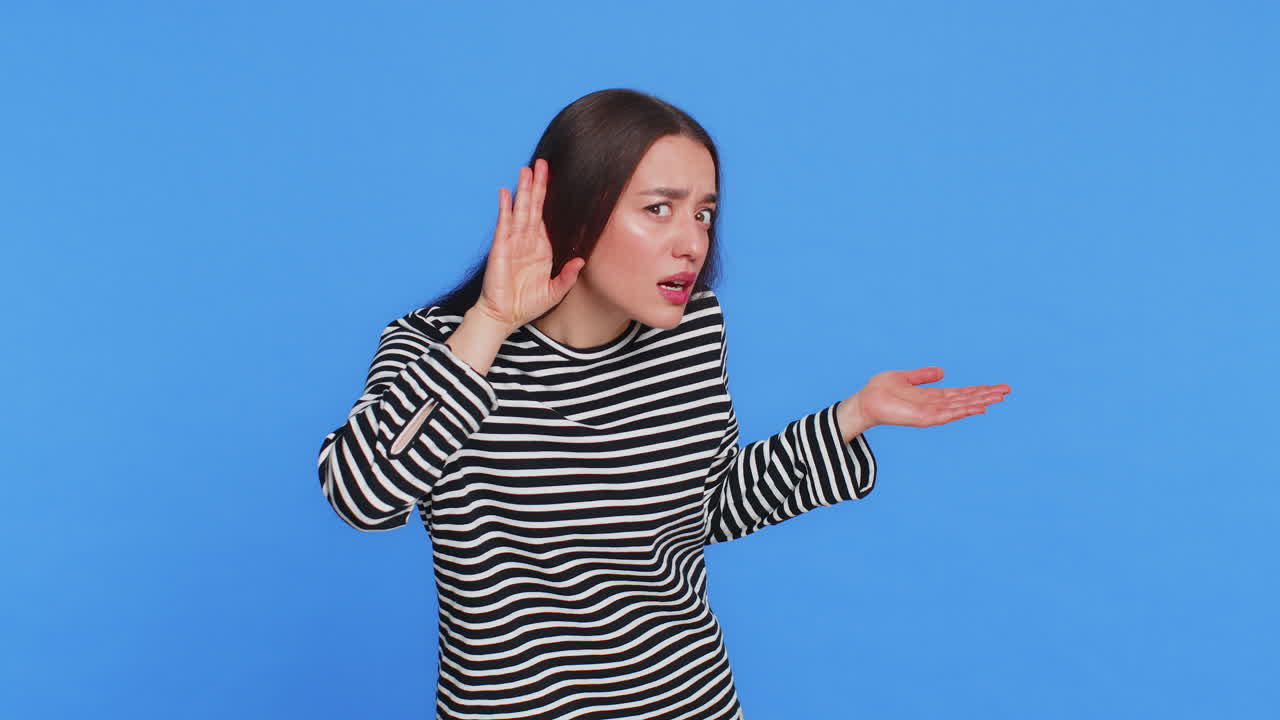 Caucasian woman trying hear you looking confused and frowning keeping arm near ear for louder voice