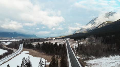 Winter-Landscape-in-British-Columbia,-Canada-with-Car-Driving-Along-Cariboo-Highway-95-and-Cloudy-Mountains-in-the-Background