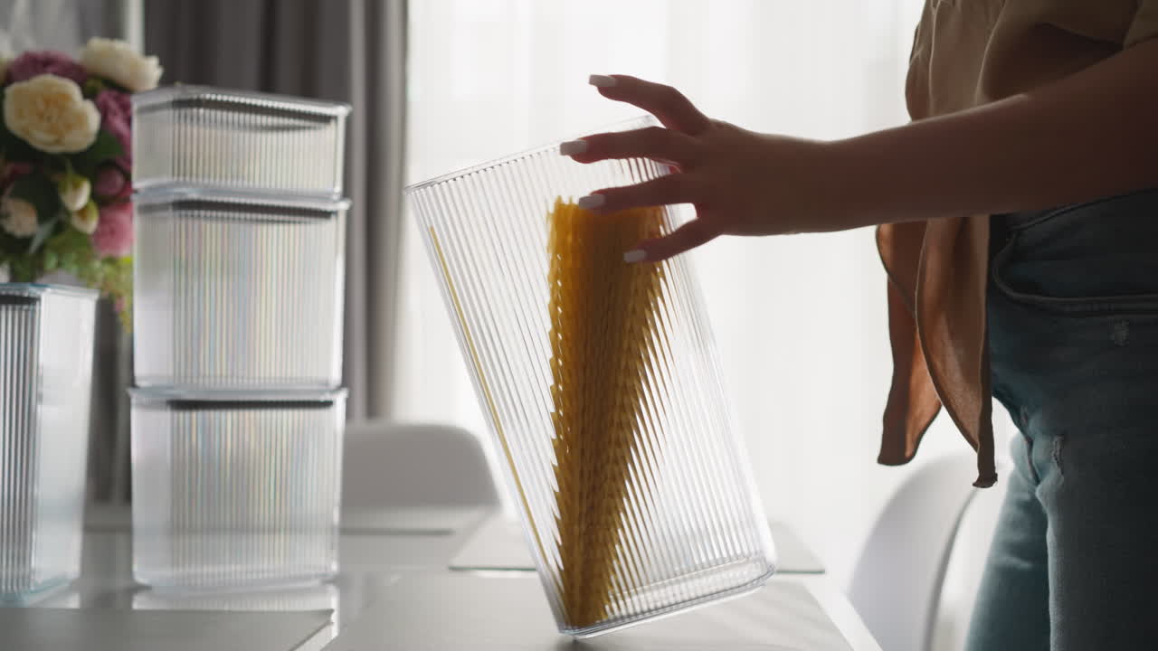 mujer gira e inclina contenedor alto con espagueti crudo