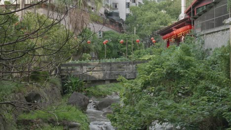 chinese lanterns hang over old bridge above small stream in asia