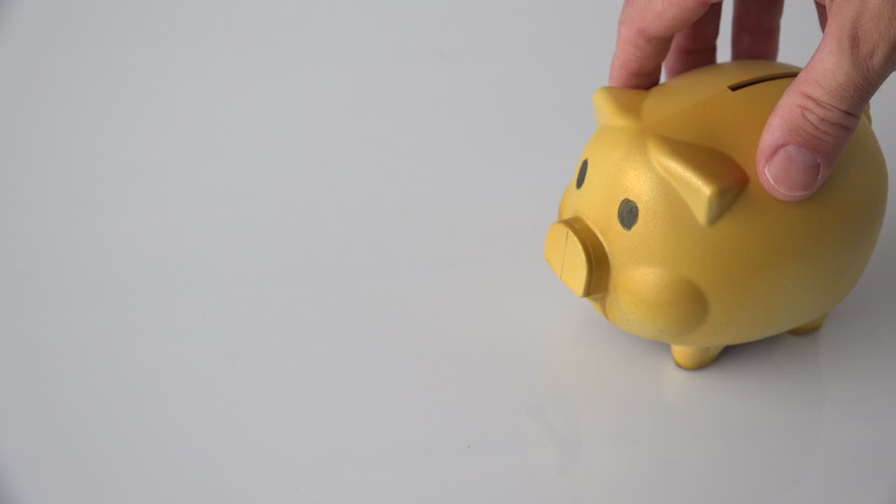 hombre jugando con el banco de monedas de cerdo dorado