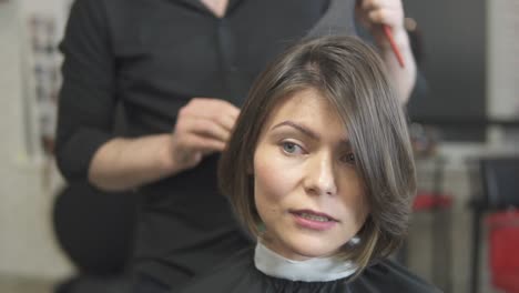 professioneller friseur, der einen spiegel verwendet, um einem kunden seinen haarschnitt zu zeigen