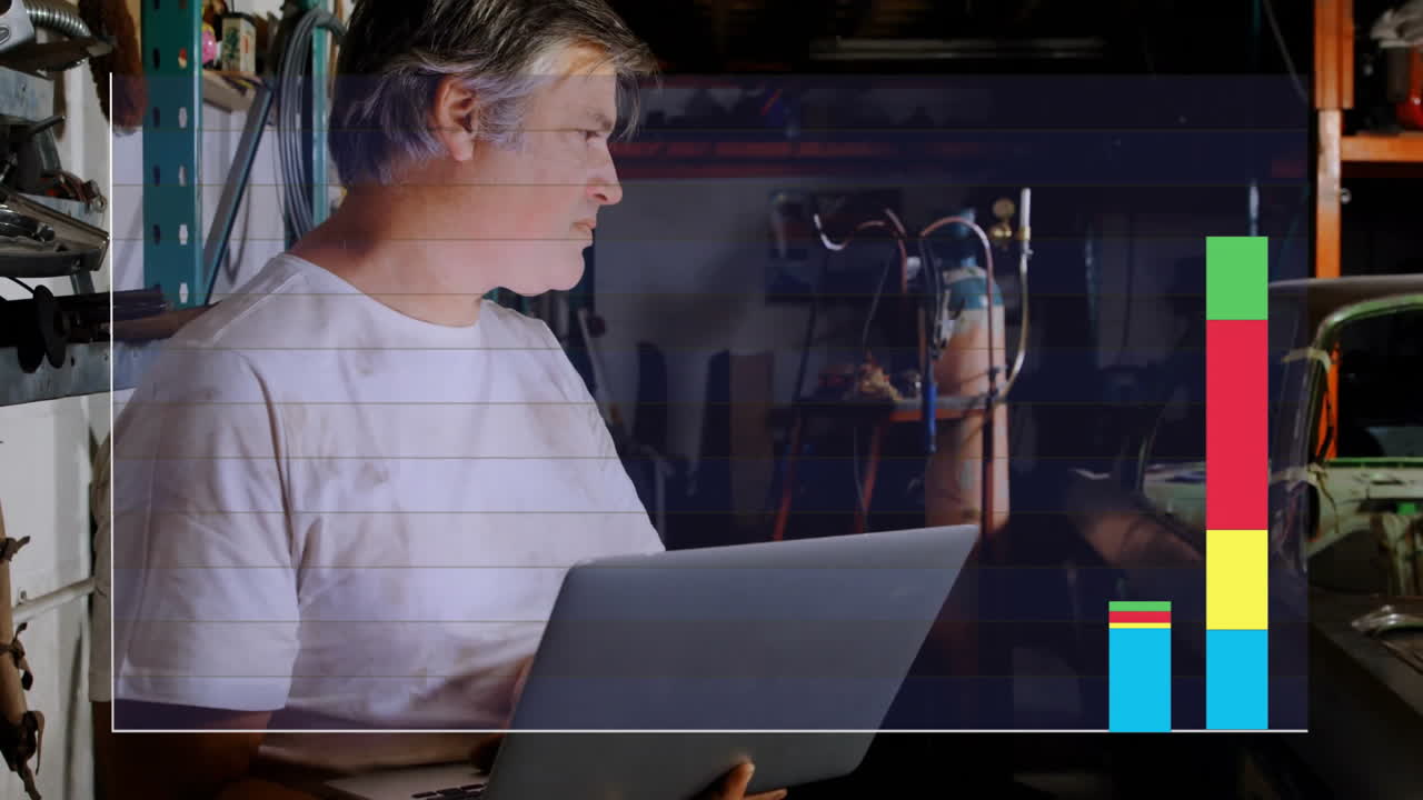 Animation of financial data processing over caucasian male mechnic using laptop in workshop