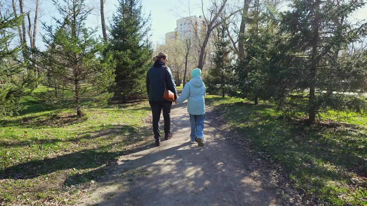 Anne ve Çocuk, Güneşli Bir Park Yolunda El Ele Yürüyor