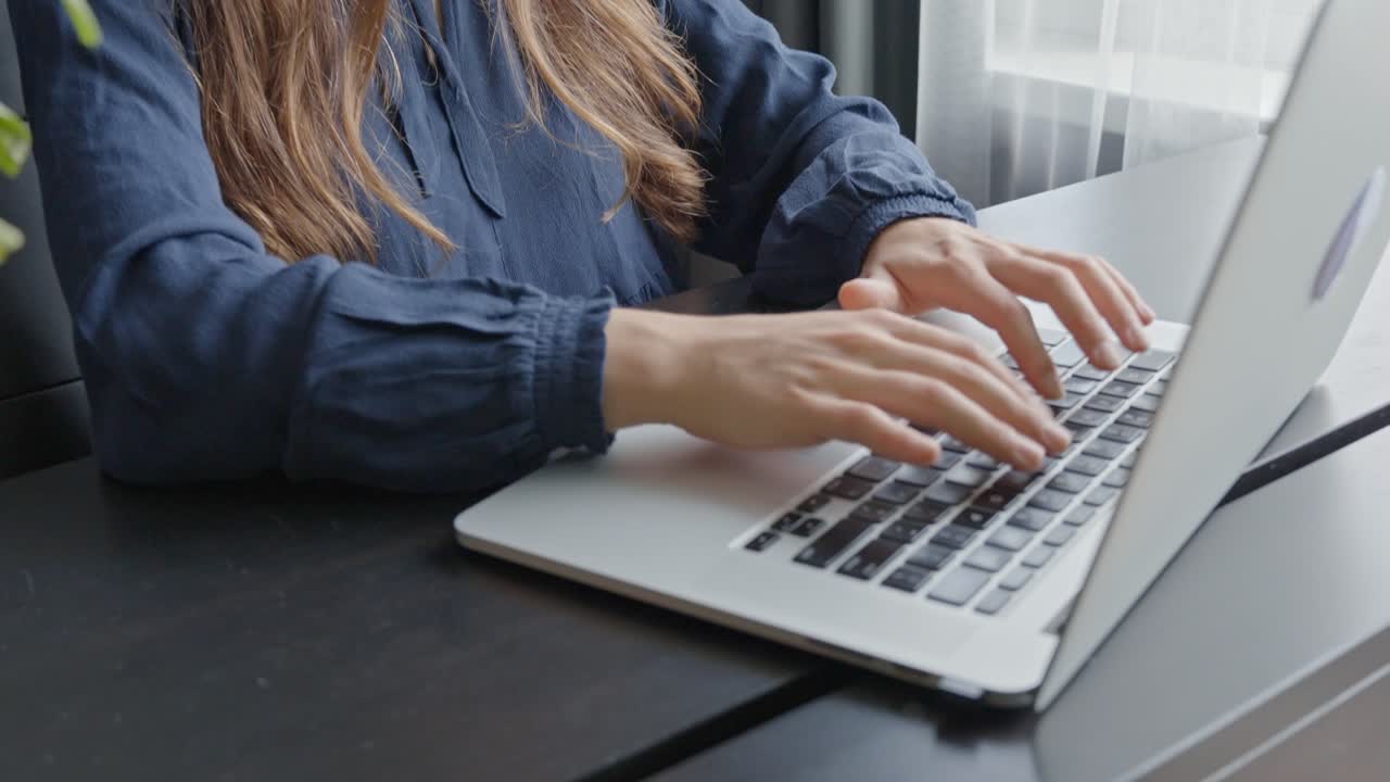 mujer joven trabajando en una computadora portátil en una pequeña oficina elegante, en cámara lenta