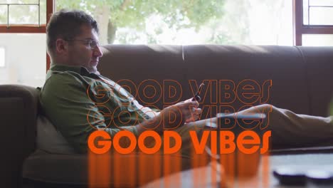 animation of good vibes text over caucasian man using smartphone