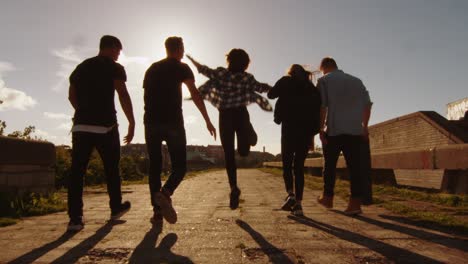 group of happy teenagers laughing, raising hands, jumping while moving outwards camera.