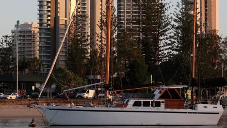 a serene view of a sailboat anchored near a city waterfront during sunset.