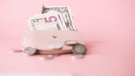 open wallet with money and coins on pink background