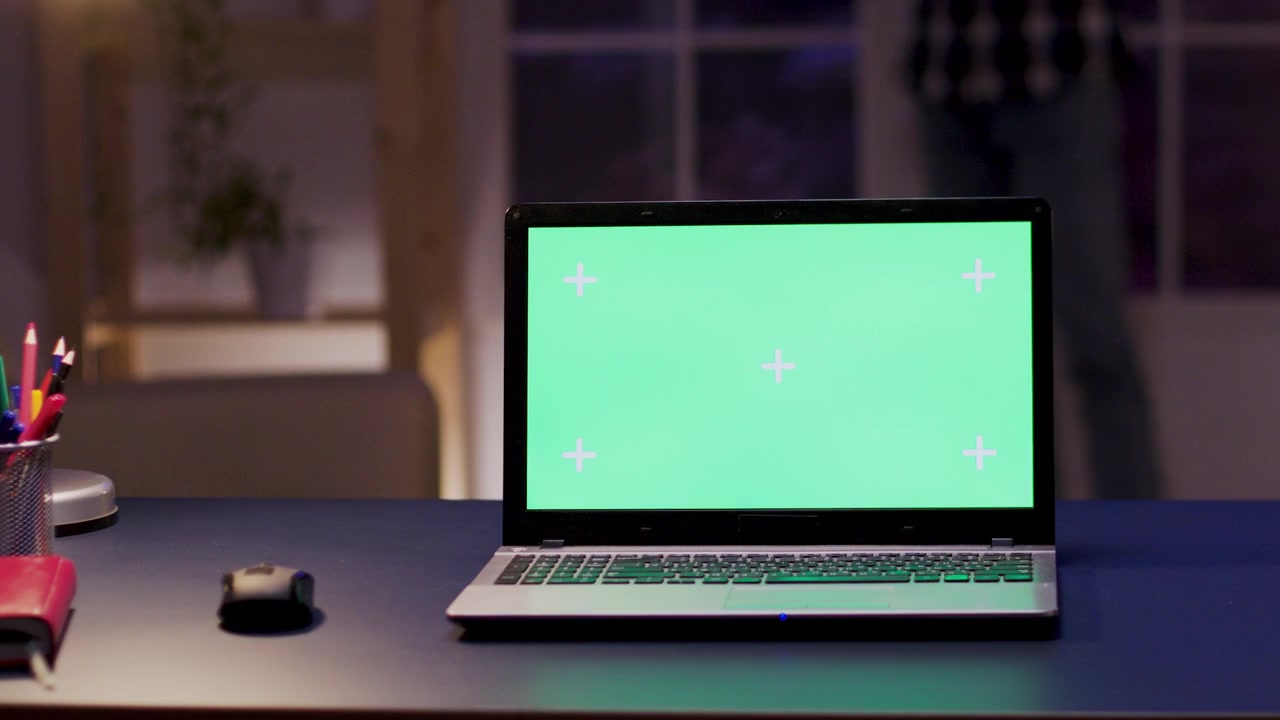 Laptop with Green Screen on Desk in Modern Office at Night