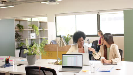 Diverse-female-creative-colleagues-in-discussion-using-laptop-in-office,-slow-motion