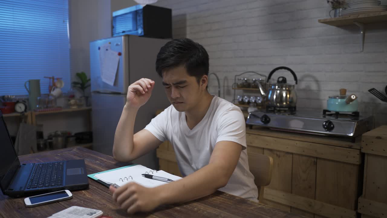 걱정스러운 아시아 남성의 느린 움직임은 은행 지폐를 공중에 던지고 숨쉬며 머리를 들고 집에서 돈 문제로 큰 불안을 느끼고 있습니다.