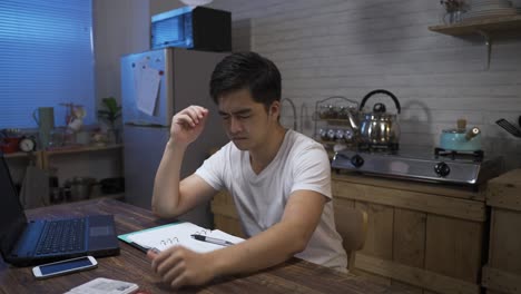 걱정스러운 아시아 남성의 느린 움직임은 은행 지폐를 공중에 던지고 숨쉬며 머리를 들고 집에서 돈 문제로 큰 불안을 느끼고 있습니다.