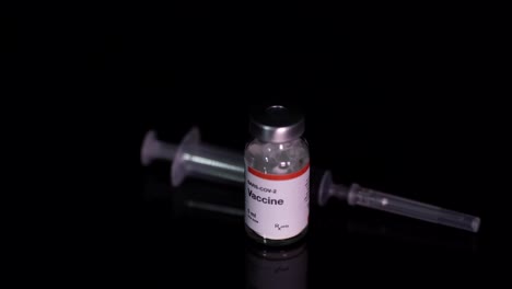 Coronavirus-vaccine-bottle-and-syringe-isolated-on-black-background