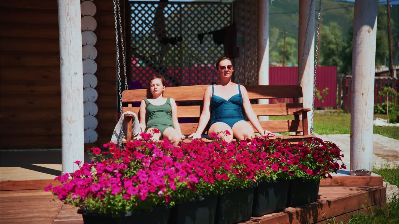 Donna e bambina che si rilassano su un'altalena all'aperto con fiori