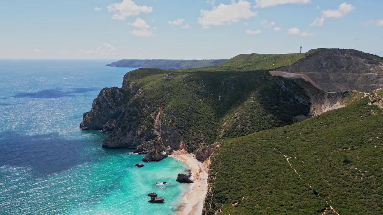 Tyrkysové vody Atlantiku, drsné útesy a odlehlá pláž Praia do Ribeiro do Cavalo poblíž Sesimbry v Portugalsku, letecký panoramatický záběr.