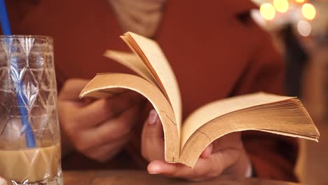 mujer leyendo un libro en un café con una taza de café