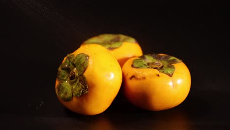 persimmons slowly rotate on a dark background