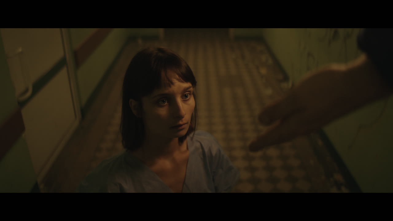 A girl and strange clown on stilts in a dark corridor at night