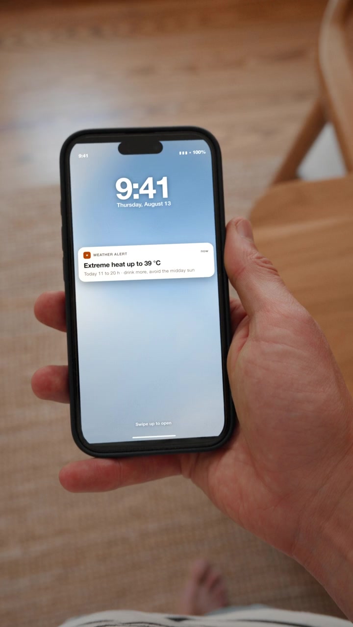 Un avviso ufficiale di caldo estremo appare sulla schermata di blocco con consigli per la giornata. Scatto in soggettiva in formato verticale con il telefono tenuto in mano. Utile per proteggere la salute durante un'ondata di calore