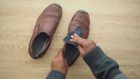 person cleaning and polishing brown leather shoes