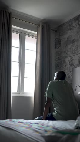 hombre mirando por la ventana mientras está sentado en una habitación de hotel bien decorada. video vertical