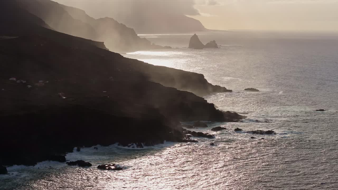 Stunning sunset over volcanic coastline of El Hierro, mist rising from cliffs