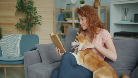 woman reading a book with her dog on the sofa